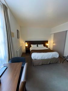 Una habitación de hotel con dos camas y un escritorio. en Hotel de Montaulbain, en Verdún