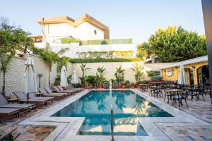 ein Pool mit Liegestühlen und Sonnenschirmen neben einem Gebäude in der Unterkunft Motif Hotel Çeşme in Cesme