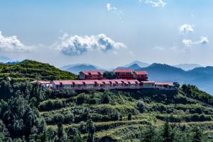 a building on a hill with mountains in the background at Aurevelle Kastura Resort Kanatal - Mountain View Rooms in Kanatal