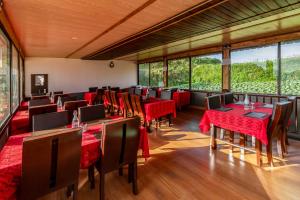 a restaurant with red tables and chairs and large windows at Aurevelle Kastura Resort Kanatal - Mountain View Rooms in Kanatal