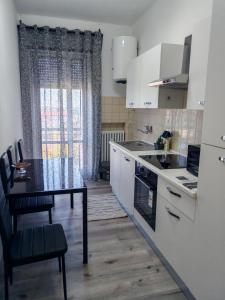 a kitchen with white cabinets and a table with a stove at Casa ALFRED FIDENZA in Fidenza