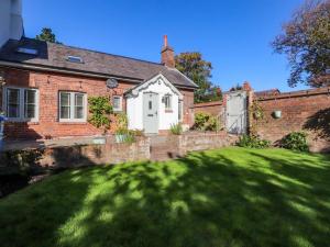 ein Backsteinhaus mit grünem Rasen davor in der Unterkunft Gardener's Cottage in Lytham St Annes