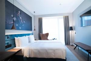 a bedroom with a large white bed and a desk at Radisson Blu Aurum Hotel, Brasov in Braşov