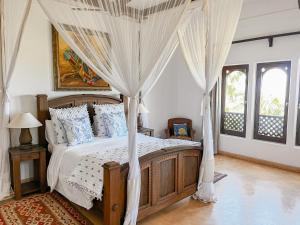 a bedroom with a canopy bed with white curtains at Vipingo Ridge, The Maridi Villa by Diplo El Homes in Pingilikani +52 photos