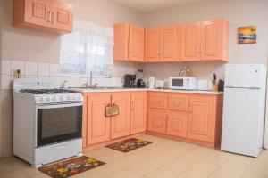 a kitchen with orange cabinets and a white refrigerator at Paradis des Palmiers 1 Gorgeous 2bedroom apartment in Belmont