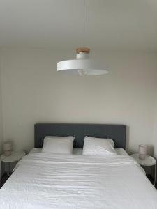 Una cama blanca con dos almohadas blancas y una luz. en Beaulivia Maaseik, en Maaseik