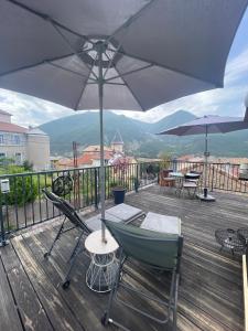 a deck with two chairs and an umbrella at L'Idylle avec accès toit terrasse in Veynes