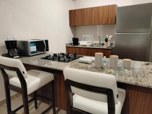 a kitchen with a counter with a stove and chairs at Luxury 2-Bedroom Apartment with amazing view - Infinity Pool and Rooftop in Building in Veracruz