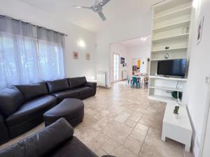 ein Wohnzimmer mit Sofa und Fernseher in der Unterkunft Villa nel Salento con piscina e ulivi in Nardò
