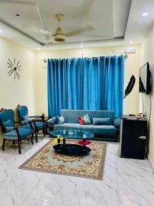 a living room with a blue couch and blue curtains at 1 one bed flat furnished Bahria Town Rawalpindi Islamabad in Rawalpindi
