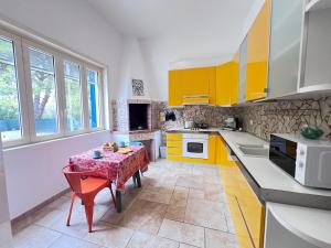 eine Küche mit gelben und weißen Schränken und einem Tisch in der Unterkunft Villa nel Salento con piscina e ulivi in Nardò
