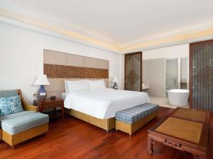 une chambre avec un grand lit blanc et une chaise dans l'établissement Swissôtel Sanya Yalong Bay, à Sanya