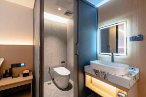 Un baño con lavabo, inodoro y espejo. en Ban Shan Du Hotel, en Yangshuo