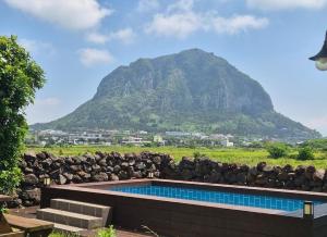 une piscine avec une montagne en arrière-plan dans l'établissement 제주 웅장한 산방산뷰 사계2248 해무리동 감성숙소, à Sagye-ri