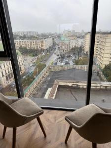 two chairs sitting in front of a large window at TM Panoramic apartament centru in Iaşi