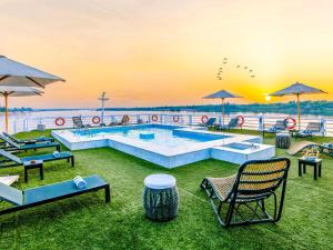 a pool with chairs and umbrellas on the grass at Mövenpick MS Sunray in Luxor +90 photos