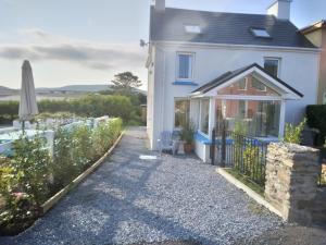a white house with a garden and an umbrella at Seod Na Mara, Jewel of the Sea, Upstairs Flat, Dun Geagan,Ballinskelligs in Ballinskelligs