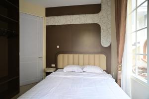 a bedroom with a bed with white sheets and a window at Maison Belle in Tlekung +12 photos