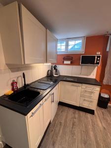 Una cocina con gabinetes blancos y una encimera negra. en Le secret de Saint-Maur, en Rouen