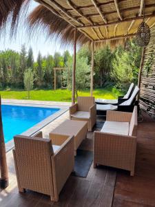 a patio with wicker furniture and a swimming pool at Villa malak in Aït Imouni