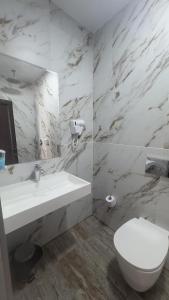 a white bathroom with a sink and a toilet at Hotel Garden in Vidin