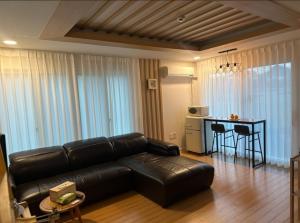 a living room with a black leather couch and a table at 제주 웅장한 산방산뷰 사계2248 달무리동 감성숙소 in Sagye-ri