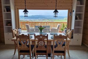 a dining room with a table and chairs and a large window at Widokówka Kluszkowce in Kluszkowce