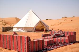 a tent and several chairs in the desert with a rug at Authentic Private Tent in Badīyah