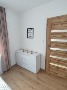 シュツァブニツァにあるApartamenty JULKAの白いドレッサーと木製のドアが備わるベッドルーム1室