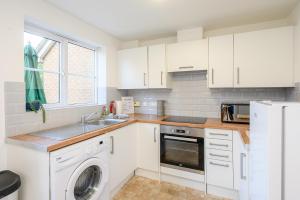 La cuisine est équipée de placards blancs et d'un lave-vaisselle. dans l'établissement Quiet House, PRKG-3 Cars, Contractors & Families, York Centre 10mins, à York