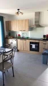 a kitchen with wooden cabinets and a table and a chair at Meublé de tourisme classé 3 étoiles Le Ptit Coin de Soleil - Saint Ciers d'Abzac in Saint-Ciers-dʼAbzac