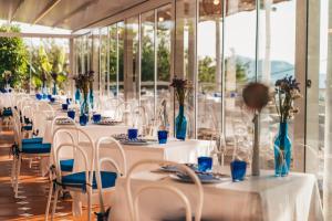 a row of tables with white chairs and blue vases at Gocce Di Capri Resort in Massa Lubrense
