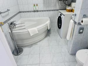 a bathroom with a tub and a washing machine at Európa Apartman Mini in Békéscsaba +11 photos