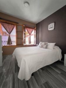 a bedroom with a large white bed with two windows at Casita Piedra Escrita - Private & Exclusive House in Córdoba