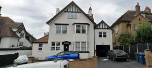 un coche azul estacionado frente a una casa blanca en Bright 2-Bed Flat with Free Parking near Whetstone, en New Barnet