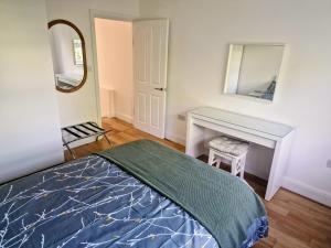 Un dormitorio con una cama, un escritorio y un espejo. en Bright 2-Bed Flat with Free Parking near Whetstone, en New Barnet