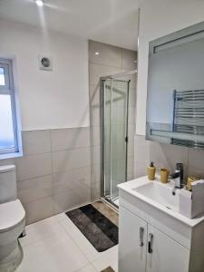 Un baño blanco con ducha y lavabo. en Bright 2-Bed Flat with Free Parking near Whetstone, en New Barnet