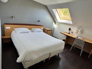 a bedroom with a bed and a desk and a window at Campanile Saumur in Saumur