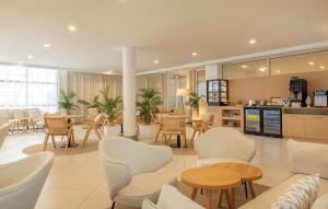 Un vestíbulo con mesas y sillas y una cafetería. en Alua Gran Camp de Mar, en Camp de Mar
