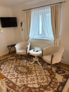 a living room with two chairs and a table and a window at Vila Gabriel in Sinaia