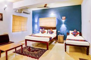 a bedroom with two beds and a blue wall at Via Elvin Balaji Beach Palace - 500m From Calangute Beach in Goa