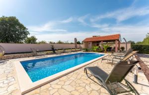 a swimming pool with chairs and a house at 5 Bedroom Cozy Home In Biograd Na Moru in Biograd na Moru