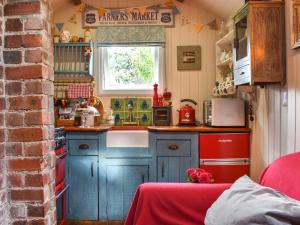 a small kitchen with blue cabinets and a sink at Y Golchdy in Llangadog