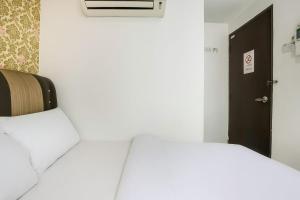 a bedroom with a white bed and a black door at Hotel Melaka INN in Melaka