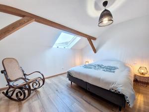 ein Schlafzimmer mit einem Bett und einem Stuhl auf einem Dachboden in der Unterkunft L'ECRIN DU BONHEUR - Neuf - Tout confort - Parking - Proche de Strasbourg - Spacieux - Proche Transports in Stutzheim