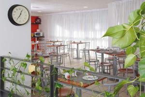 a restaurant with tables and chairs and a clock at Séjours & Affaires Paris Ivry in Ivry-sur-Seine