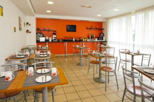 un restaurante con paredes de color naranja, mesas y sillas en Séjours & Affaires Paris Ivry, en Ivry-sur-Seine