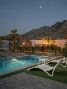 a swimming pool with two chairs next to a building at 800 Mountain Resort Vacation House in Fujairah