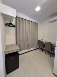 une chambre avec une table, des chaises et un rideau dans l'établissement Anexxo HC, à Palhoça