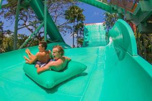 zwei Jungen reiten auf einer Wasserrutsche in einem Wasserpark in der Unterkunft ABI Hotel4 - 1 minute to the Beach and 1 second to the Mall in Ngurah Rai International Airport
